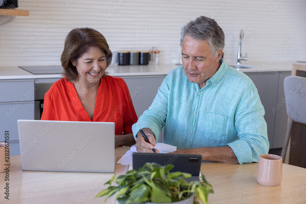 Couple reviewing documents at home with laptop
